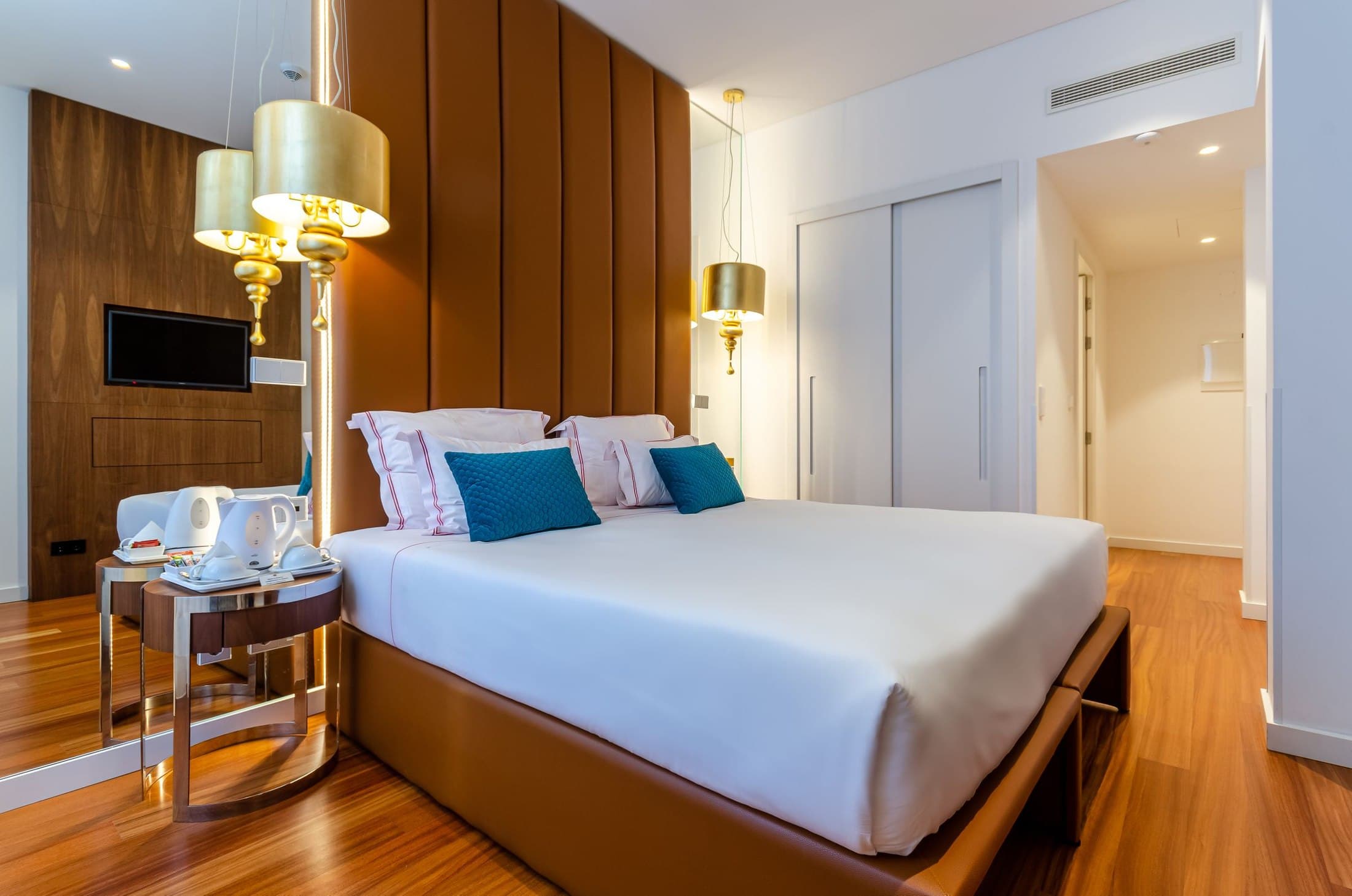 Lisbon hotel bedroom with layered lamps, a bench and a clear route to the door