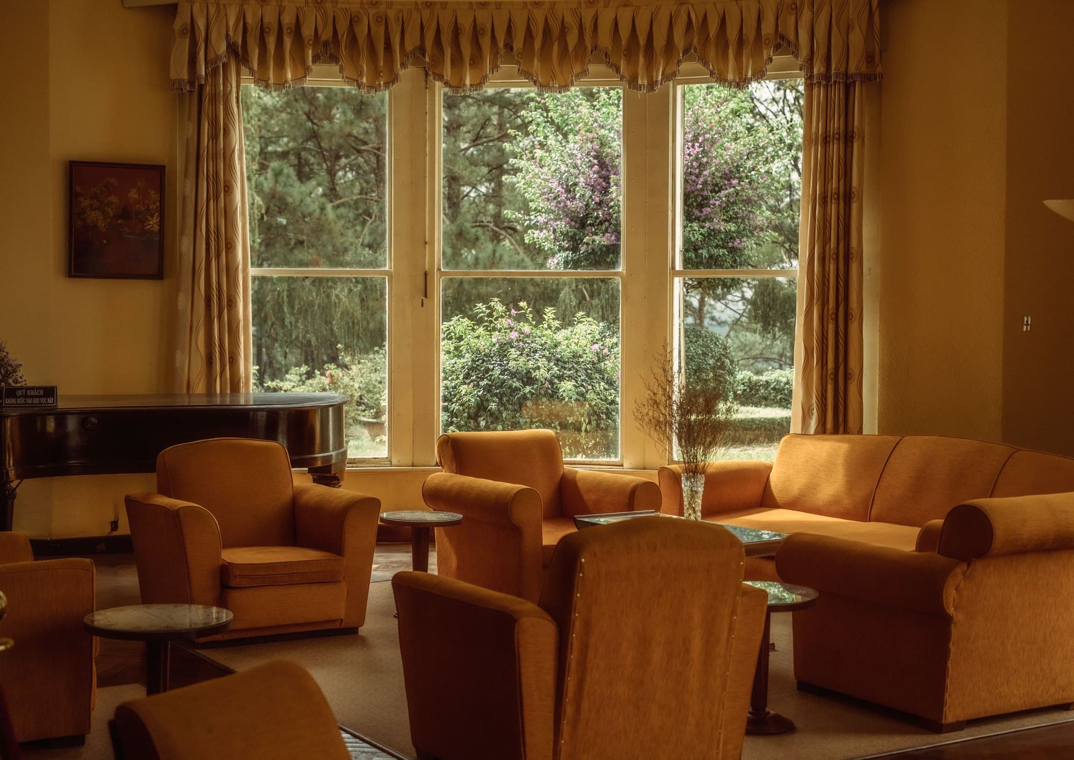 Sunlit living room arranged with vintage armchairs, sofa and piano