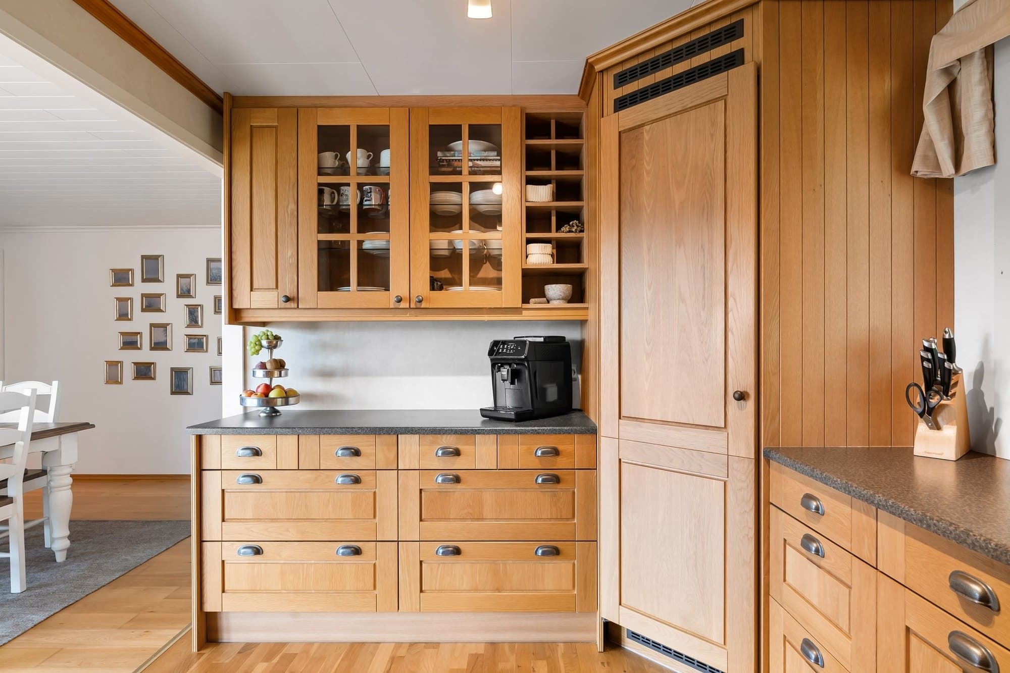 Oak kitchen cabinetry and a timber dining table in warm daylight