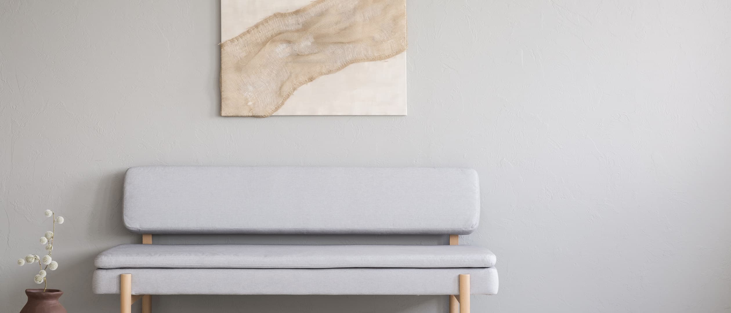 A curved two-seat sofa in a sunlit living room, with a round coffee table.
