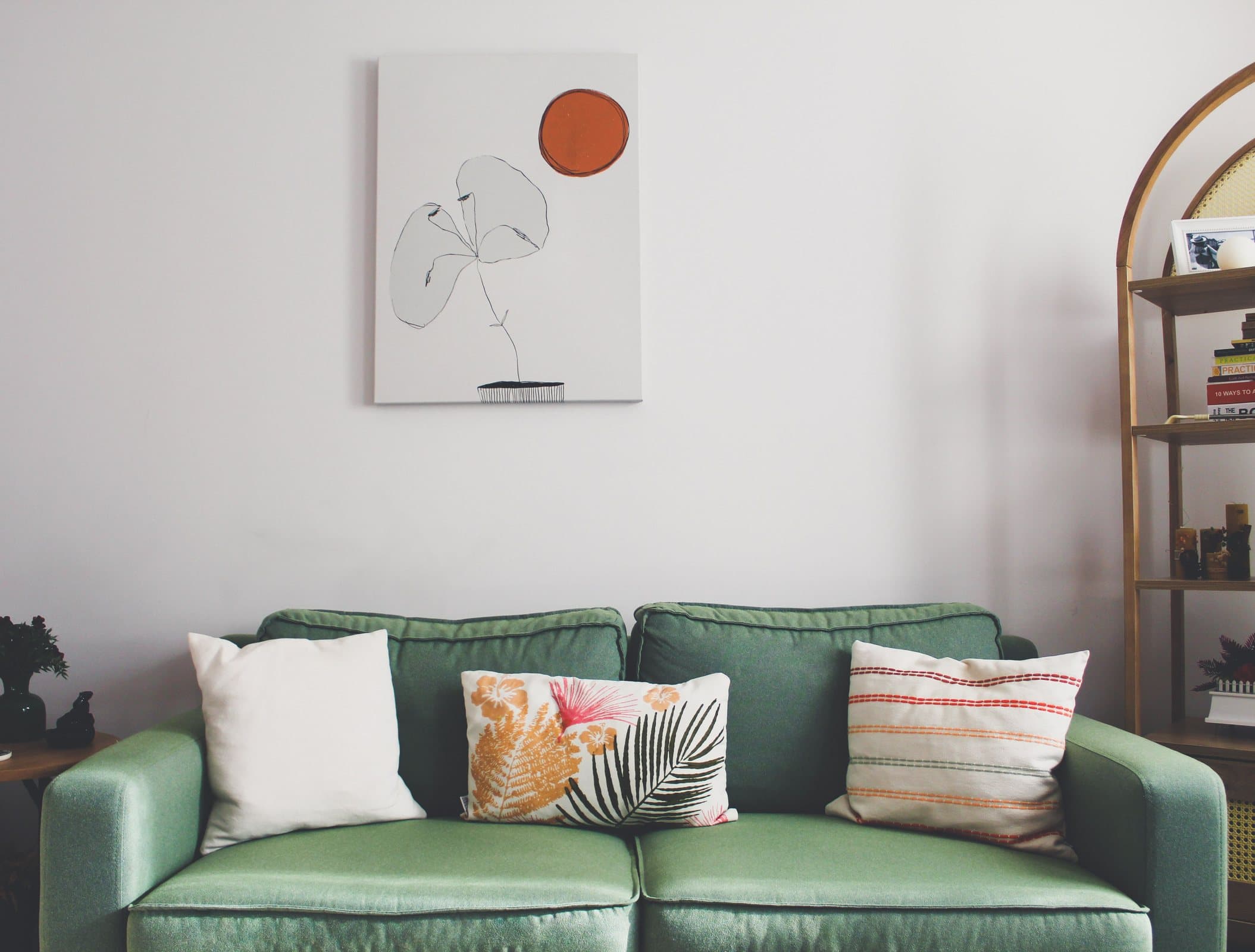 Abstract artwork hung above a green sofa in a restrained living room