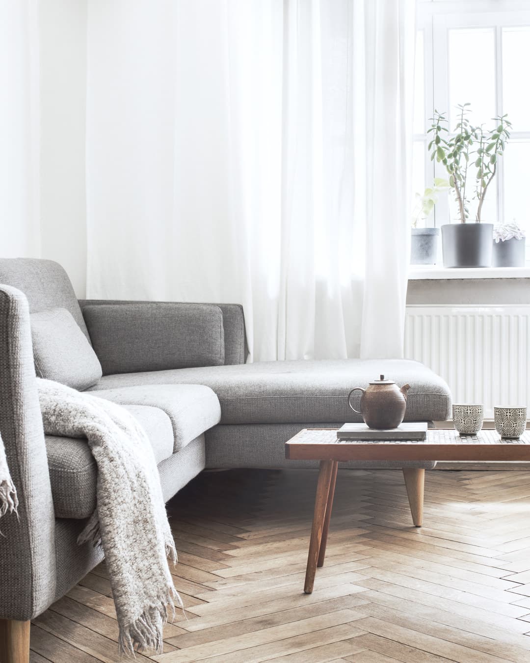 Woonkamer in daglicht met een grijze bank en een eiken salontafel